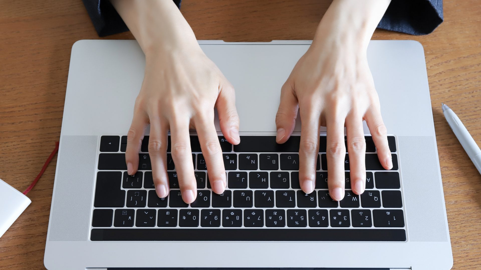 人の手が、日本語配列のノートパソコンのキーボードの上にあるクローズアップ。