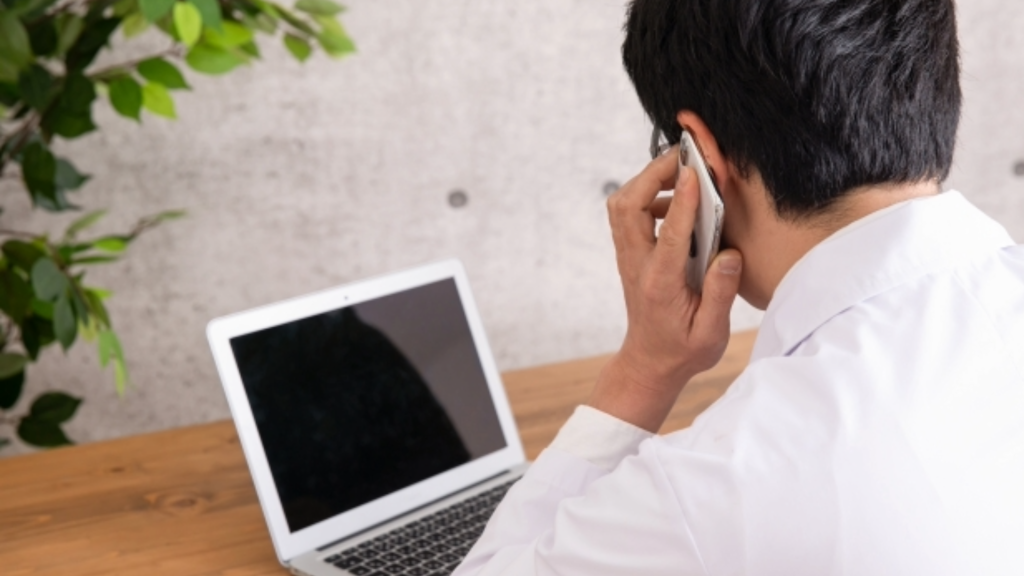 Macで外付けHDDがどうしても認識しない場合に、専門のサポート窓口やデータ復旧業者へ電話で相談・問い合わせをしている様子