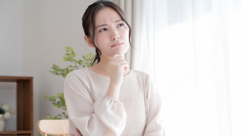 データ復旧業者の選び方に悩み、どのおすすめ業者が最適か比較検討している女性。背景には観葉植物があり、落ち着いた雰囲気で思案しています。