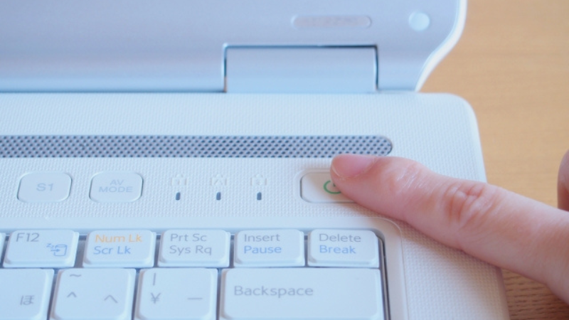 パソコンの電源ボタンを押す指先。SSDのデータ復旧において通電を避ける説明