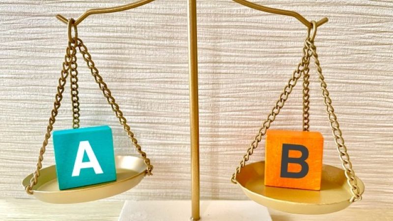 データ復旧専門業者とメーカー修理の違いを、天秤に乗ったAとBのブロックで比較・検討する図解。