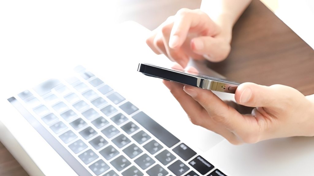 データ復旧ソフトを使うためにノートパソコンの上でスマホを操作している様子