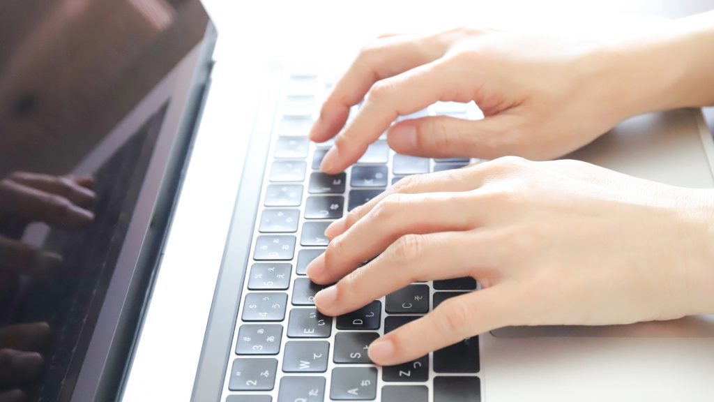 自動修復が終わらない時の対処法として、コマンドプロンプト入力などのPC操作を行う様子。ノートパソコンでタイピングする両手。