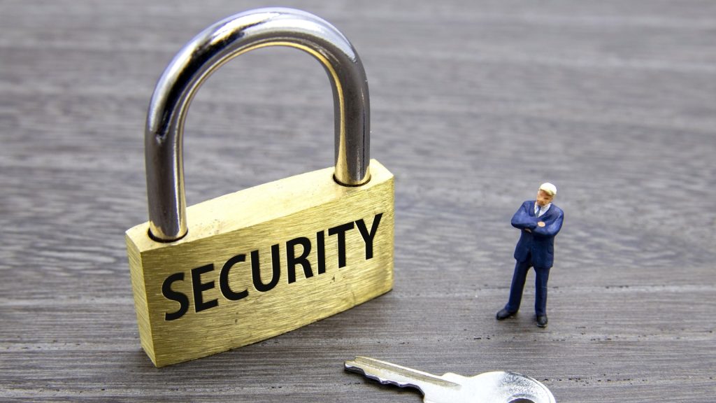 HDD復旧業者の選定で重要な情報セキュリティ対策を象徴する、SECURITYと刻まれた頑丈な南京錠とそれを見守る人物。