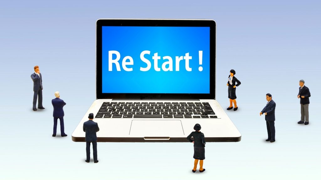 Windowsの自動修復が終わらない時の対処法である「再起動」をイメージ。ノートパソコンの画面にRe Start！の文字が表示され、解決を待つビジネスパーソンの様子。