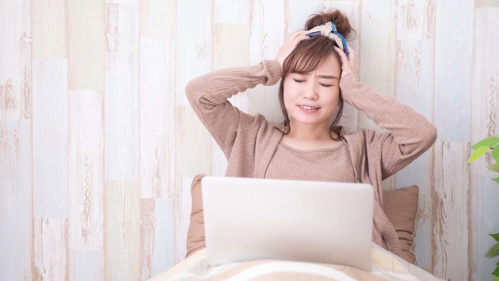 ゴミ箱にファイルが見つからず、データの紛失にショックを受けてパソコンの前で途方に暮れる女性。