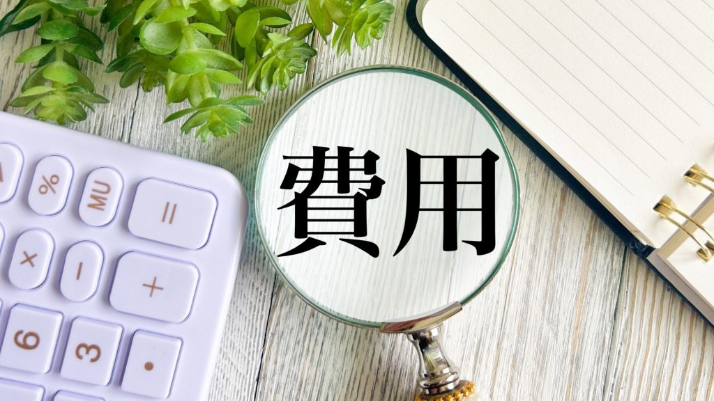 HDD復旧サービスにかかる費用や料金相場を把握するため、電卓の横で「費用」という文字を虫眼鏡で拡大して確認する様子。