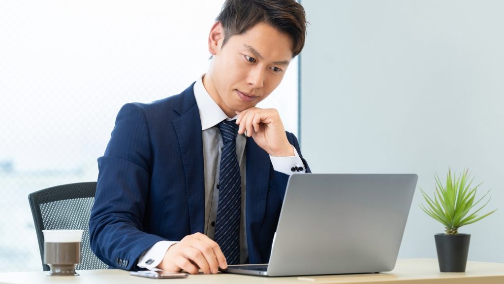 ゴミ箱から消えた重要なビジネスファイルを復元するために、パソコン画面を注視して対処法を探す男性。