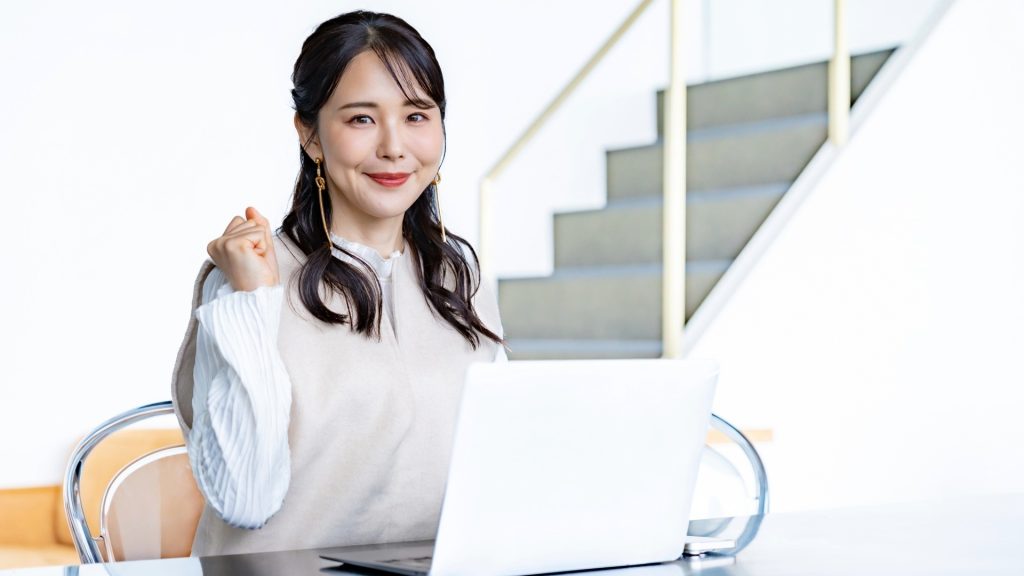Windowsの自動修復が終わらない問題が解消し、正常に起動して喜ぶユーザー。パソコンの前でガッツポーズをする女性。