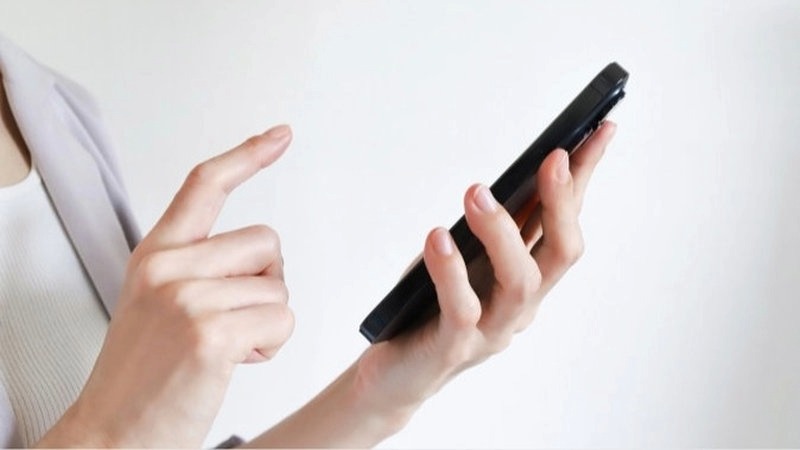 白い服を着た人物が、黒いケースをつけたスマホを持ち、データ復旧方法を模索している